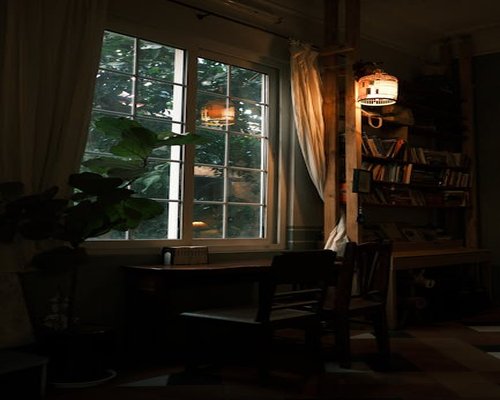A well lit desk next to a window with soft semi-transparent curtains